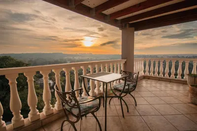 a table and chairs on a balcony with a sunset at All Seasons Boutique Hotel - Sustainable Electricity and Water in Pretoria