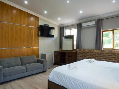 a bedroom with a bed and a couch and a television at Hotel @ Secunda in Secunda