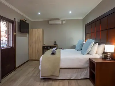 a bedroom with a large bed with blue pillows at Hotel @ Secunda in Secunda