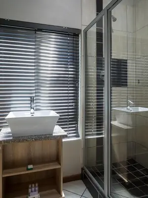 a bathroom with a sink and a glass shower at Hotel @ Secunda in Secunda