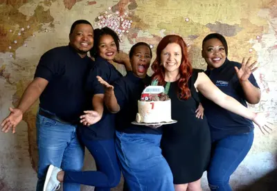 a group of people posing for a picture with a cake at 3@Marion Guest House in Pretoria