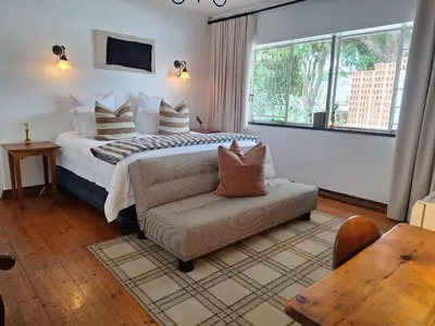 a bedroom with a bed and a couch and a window at 3@Marion Guest House in Pretoria