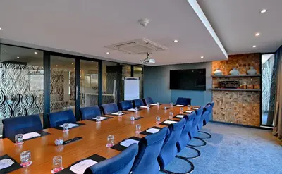 a conference room with a long table and blue chairs at City Lodge Hotel Waterfall City in Midrand
