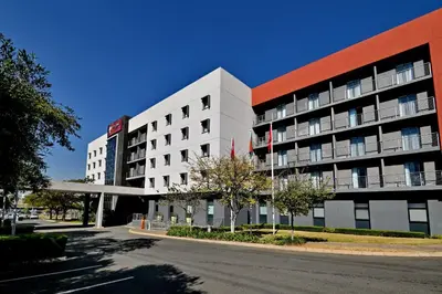 a large white building on a street next to a road at City Lodge Hotel Waterfall City in Midrand