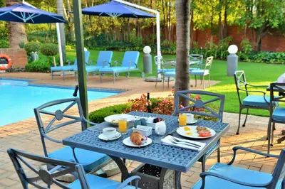 a table with food on it next to a pool at Town Lodge Menlo Park in Pretoria