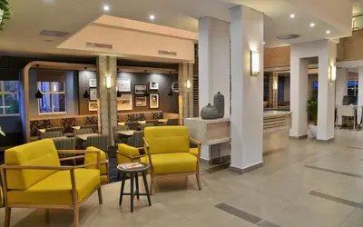 a lobby with yellow chairs and a bar at Town Lodge Menlo Park in Pretoria