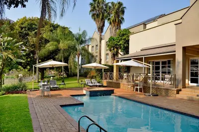 a swimming pool with tables and chairs and umbrellas at Town Lodge Mbombela in Nelspruit