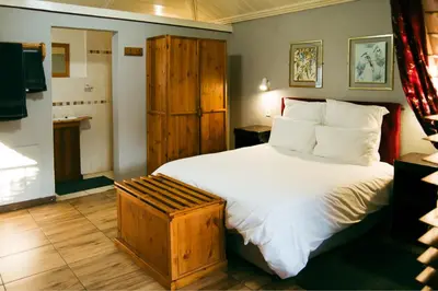 a bedroom with a large bed with a wooden cabinet at The Grey's Inn in Machadodorp