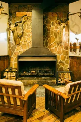 two chairs in front of a stone fireplace at The Grey's Inn in Machadodorp