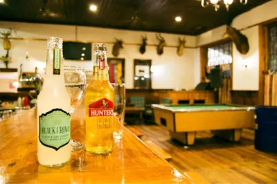 two bottles of beer sitting on top of a bar at The Grey's Inn in Machadodorp