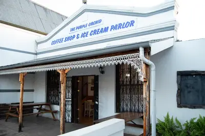 a white building with a sign that reads coffee shop and ice cream plantation at The Grey's Inn in Machadodorp