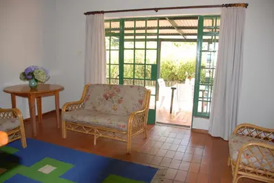 a living room with a chair and a sliding glass door at Kloofsig Holiday Cottages in Graskop