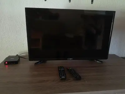 a television with two remote controls on a wooden table at Kloofsig Holiday Cottages in Graskop