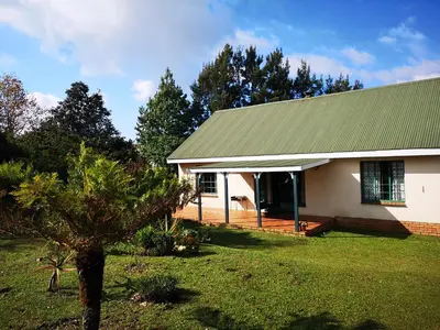 a small white house with a green roof at Kloofsig Holiday Cottages in Graskop