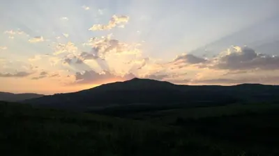 a sunset over the mountains with a rainbow in the sky at Kloofsig Holiday Cottages in Graskop