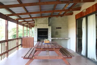 a wooden picnic table on a porch with a fireplace at The Stix in Dullstroom
