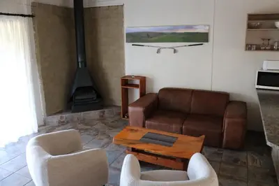a living room with a couch and chairs and a stove at The Stix in Dullstroom