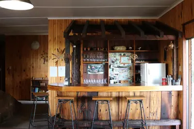 a bar in a room with chairs and a refrigerator at The Stix in Dullstroom
