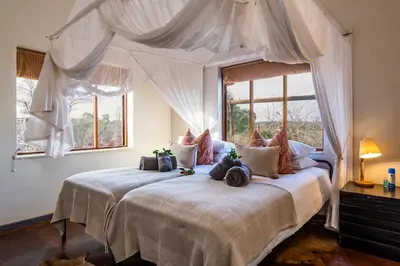 a bedroom with a large bed with white curtains at Baobab Hill House by RETURN Africa in Makuleke Contract Park