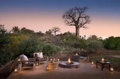 a patio with a fire pit and chairs and a tree at Baobab Hill House by RETURN Africa in Makuleke Contract Park