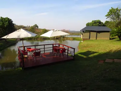 a wooden deck with tables and umbrellas on a river at Eden Cottage in White River