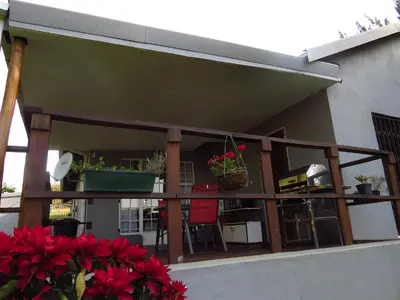 a balcony with red chairs and potted plants at Eden Cottage in White River