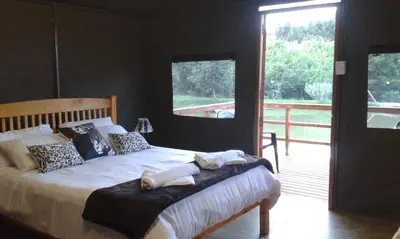 a bedroom with a bed and a large window at Eden Cottage in White River