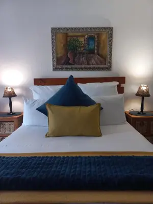 a bedroom with a large bed with blue and white pillows at J'Cups Guest House in Centurion