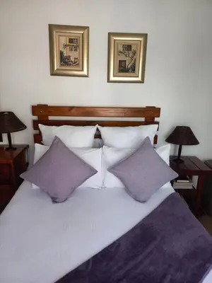 a white bed with two purple pillows and two lamps at J'Cups Guest House in Centurion