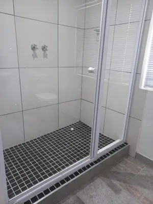 a shower with a glass door in a bathroom at J'Cups Guest House in Centurion