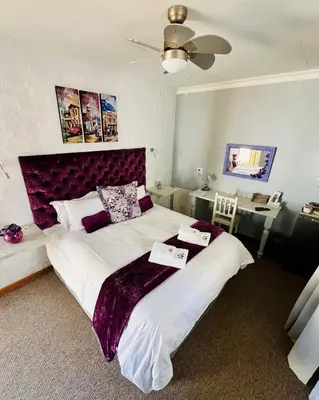 a bedroom with a large bed with a purple headboard at Longtom Farm Guesthouse in Lydenburg