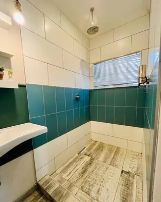 a bathroom with green and white tiles and a sink at Longtom Farm Guesthouse in Lydenburg