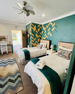 a bedroom with two beds and a ceiling fan at Longtom Farm Guesthouse in Lydenburg