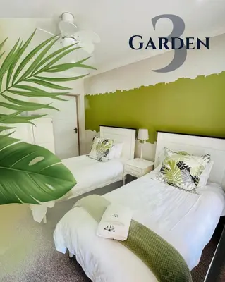 two beds in a room with a garden sign on the wall at Longtom Farm Guesthouse in Lydenburg