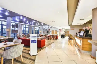 a restaurant with tables and chairs and a cafeteria at Holiday Inn Express Sandton-Woodmead by IHG in Johannesburg