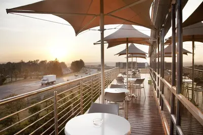 a balcony of a restaurant with tables and umbrellas at Holiday Inn Express Sandton-Woodmead by IHG in Johannesburg