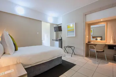 a hotel room with a bed and a desk at The Park Lodge Hotel in Pretoria