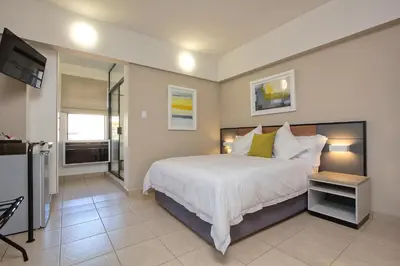 a bedroom with a large white bed and a television at The Park Lodge Hotel in Pretoria