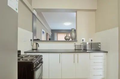 a kitchen with white cabinets and a stove and a mirror at The Park Lodge Hotel in Pretoria