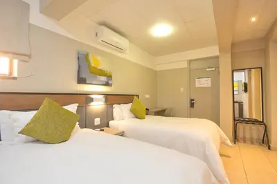 two beds in a hotel room with white sheets at The Park Lodge Hotel in Pretoria