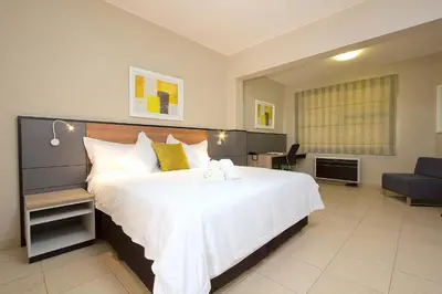 a bedroom with a large white bed and a couch at The Park Lodge Hotel in Pretoria