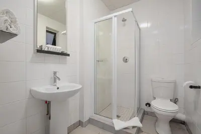 a bathroom with a shower and a toilet and a sink at The Park Lodge Hotel in Pretoria
