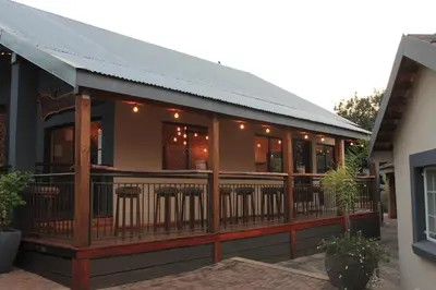 a building with a deck with chairs on it at Nelspruit Lodge in Nelspruit