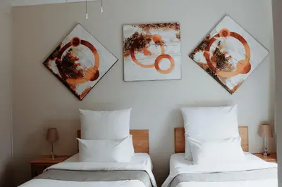 a bedroom with two beds and two pictures on the wall at Nelspruit Lodge in Nelspruit