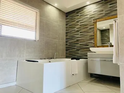 a bathroom with a tub and a sink and a mirror at Nelspruit Lodge in Nelspruit