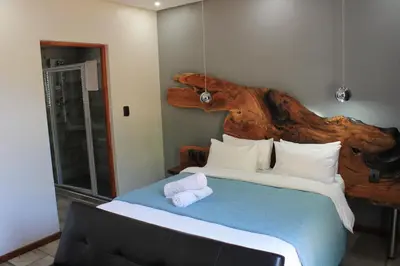 a bedroom with a large bed with a wooden headboard at Nelspruit Lodge in Nelspruit