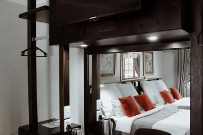 a bedroom with two beds with orange and white pillows at Nelspruit Lodge in Nelspruit