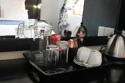 a tray with glasses and cups on a counter at Nelspruit Lodge in Nelspruit