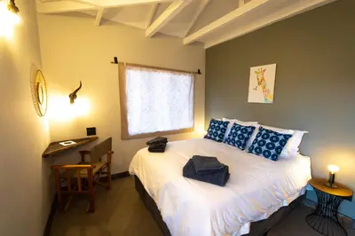a bedroom with a bed with blue pillows and a window at Antares Bush Camp & Umgede Hide in Grietjie Nature Reserve