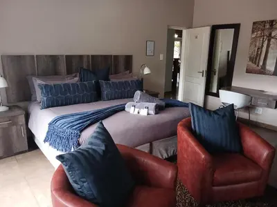 a bedroom with a large bed and two chairs at Blue Sparrow Guest House in Middelburg